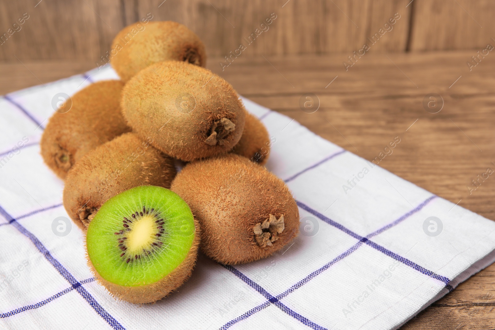 Photo of Heap of whole and cut fresh kiwis on wooden table, space for text