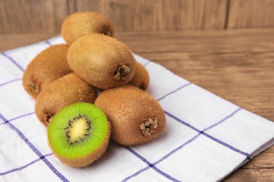 Heap of whole and cut fresh kiwis on wooden table, space for text