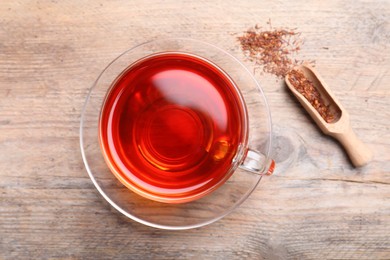 Photo of Freshly brewed rooibos tea and dry leaves on wooden table, flat lay