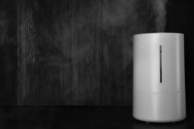 Modern air humidifier on table against wooden background. Space for text