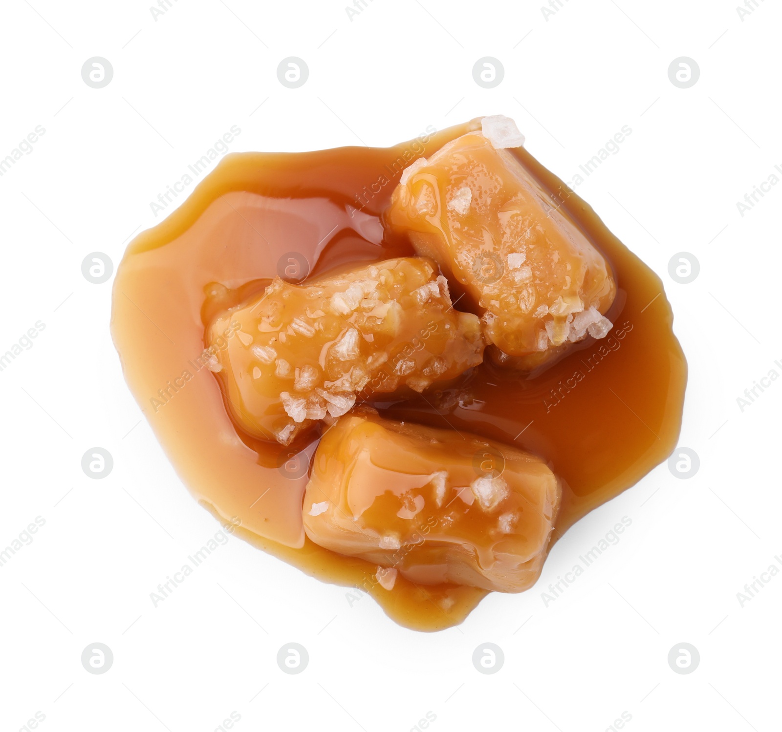 Photo of Yummy caramel candies and sea salt isolated on white, top view