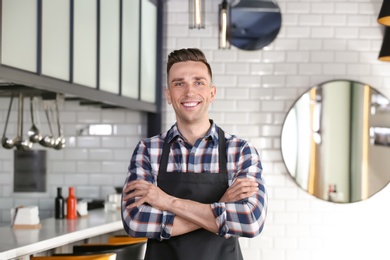 Photo of Portrait of young waiter in uniform at cafe