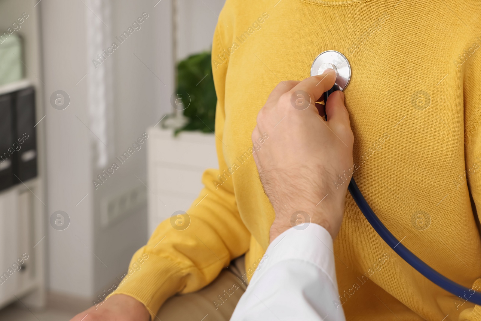 Photo of Doctor listening to patient's lungs with stethoscope in clinic, closeup