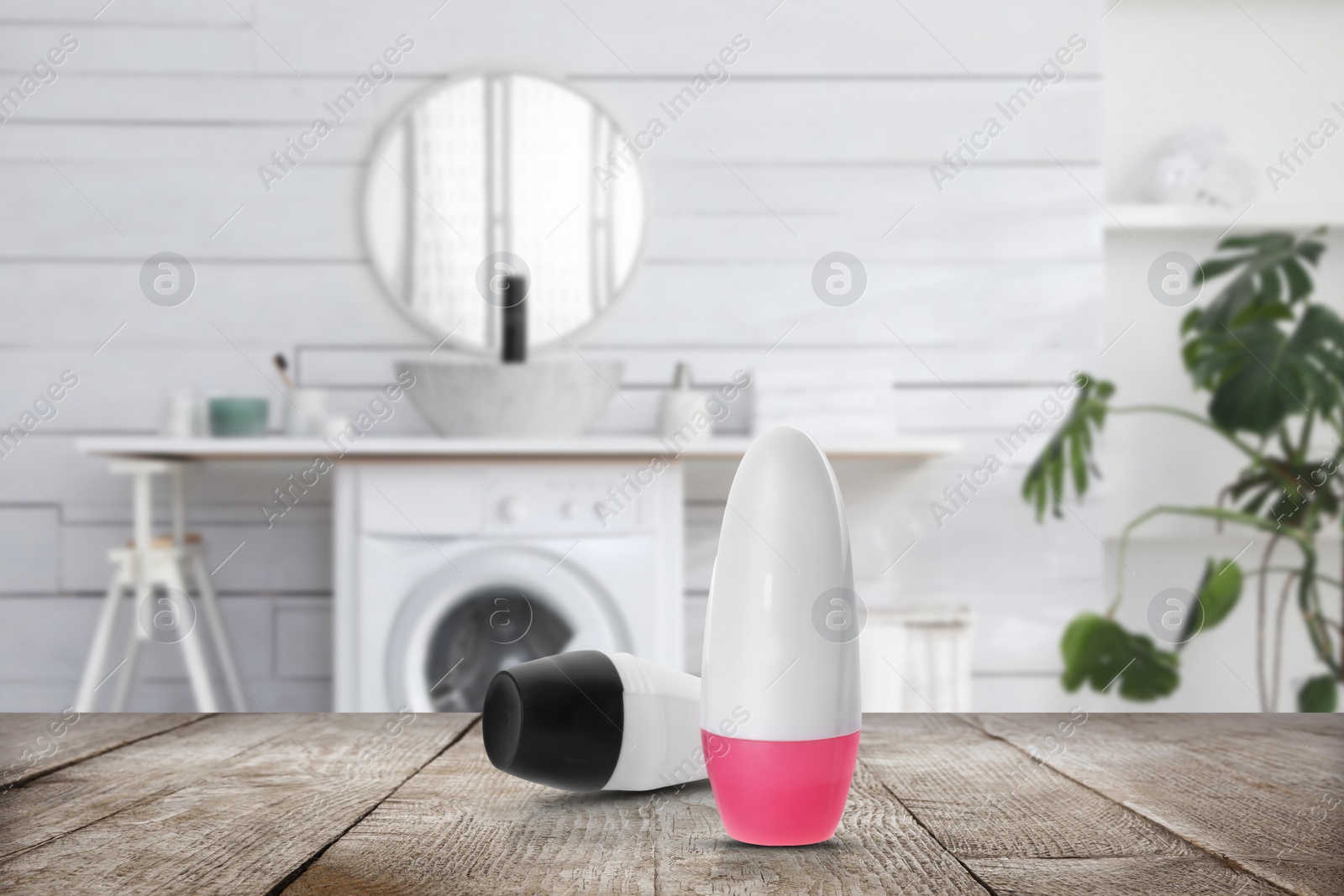 Image of Different roll-on deodorants on wooden table in bathroom. Mockup for design