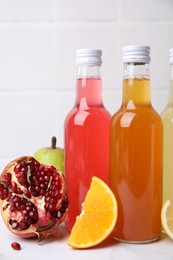 Delicious kombucha in glass bottles and fresh fruits on white table