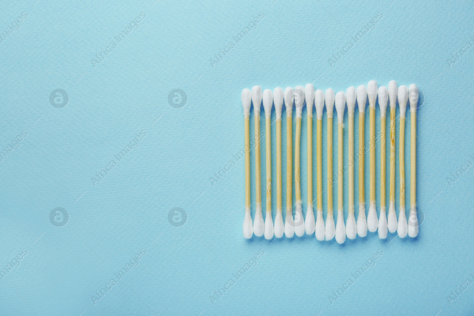 Photo of Many wooden cotton buds on turquoise background, flat lay. Space for text