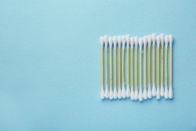 Photo of Many wooden cotton buds on turquoise background, flat lay. Space for text