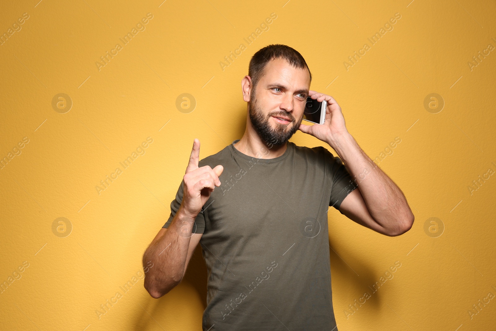 Photo of Portrait of young man with mobile phone on color background