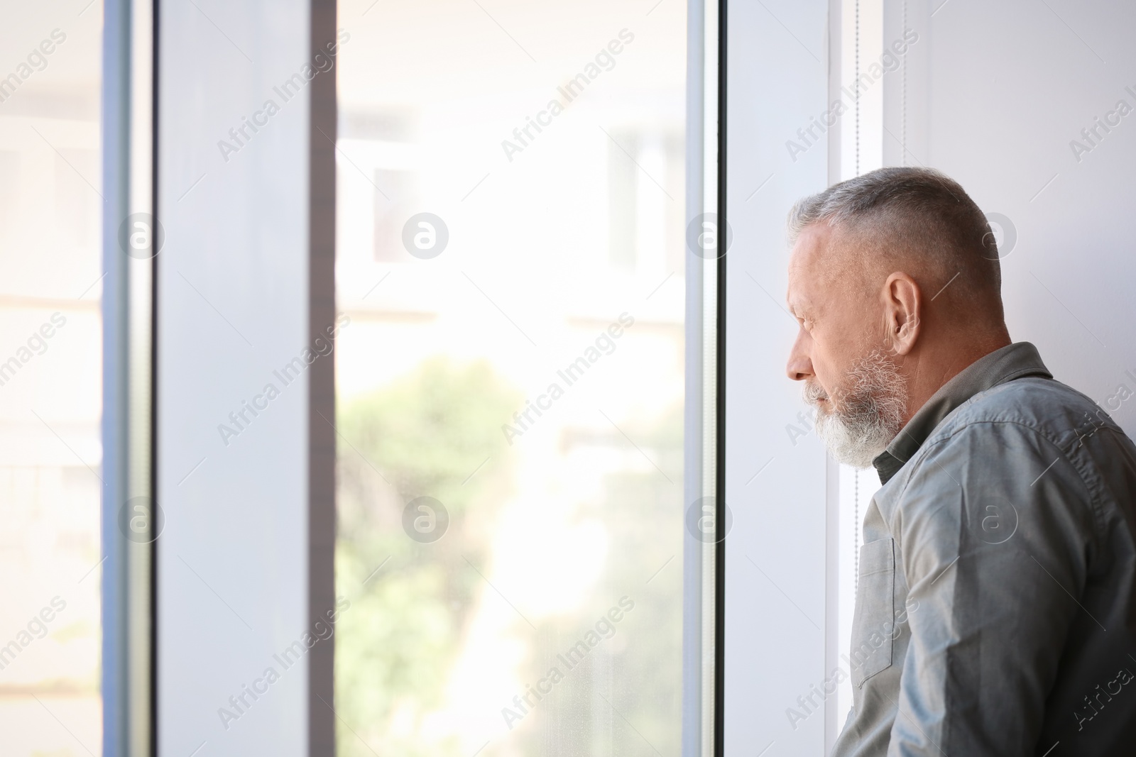 Photo of Depressed senior man near window indoors