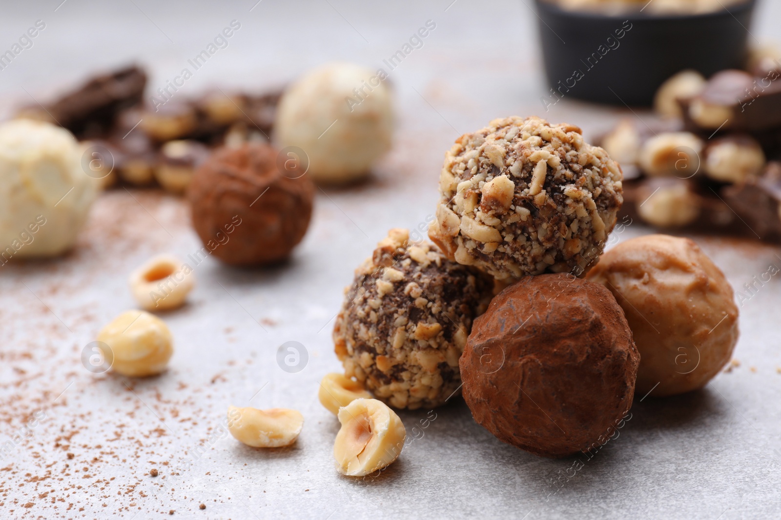 Photo of Tasty chocolate candies and nuts on light grey table, closeup. Space for text