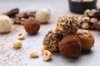 Tasty chocolate candies and nuts on light grey table, closeup. Space for text