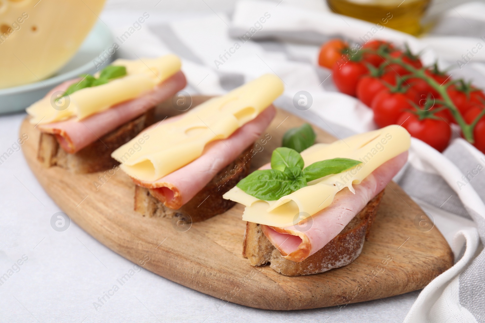 Photo of Delicious sandwiches with ham and cheese on light gray table, closeup