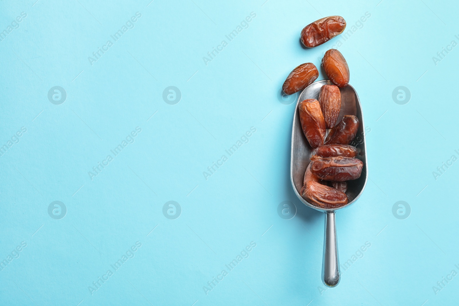 Photo of Scoop with sweet dried date fruits on color background, top view. Space for text