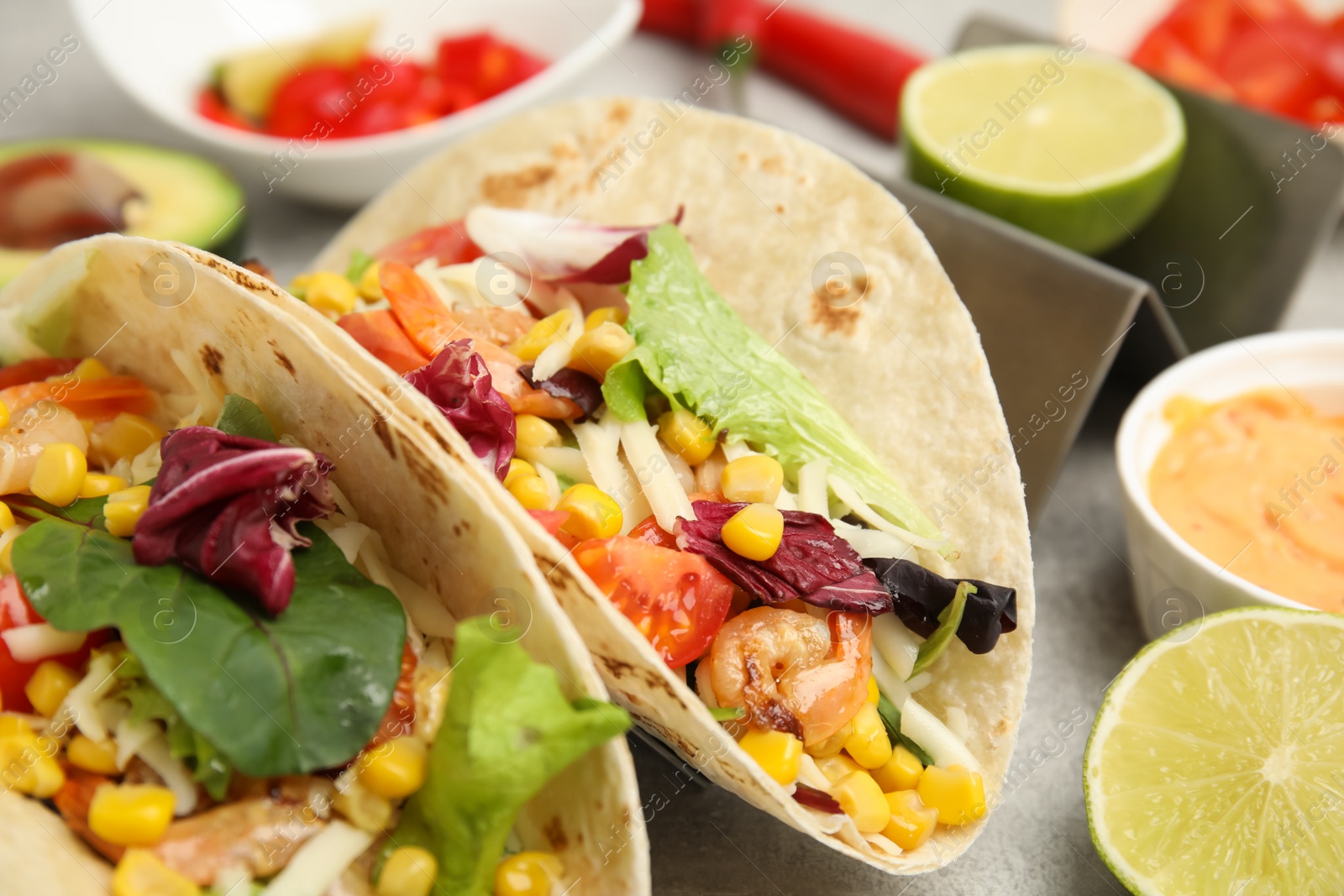 Photo of Delicious tacos with shrimps and lime on light grey table, closeup