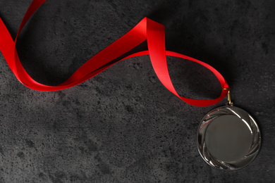 Photo of Silver medal on grey stone background, top view. Space for design