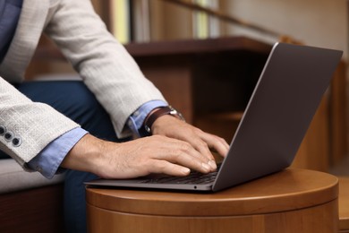 Photo of Man using modern laptop at table in cafe, closeup