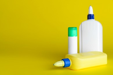 Photo of Different glues on yellow background, space for text