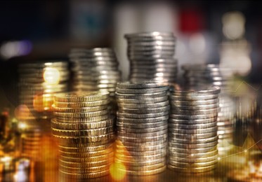 Stacked coins and charts on blurred background