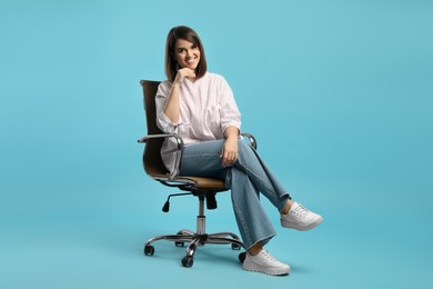 Photo of Young woman sitting in comfortable office chair on turquoise background