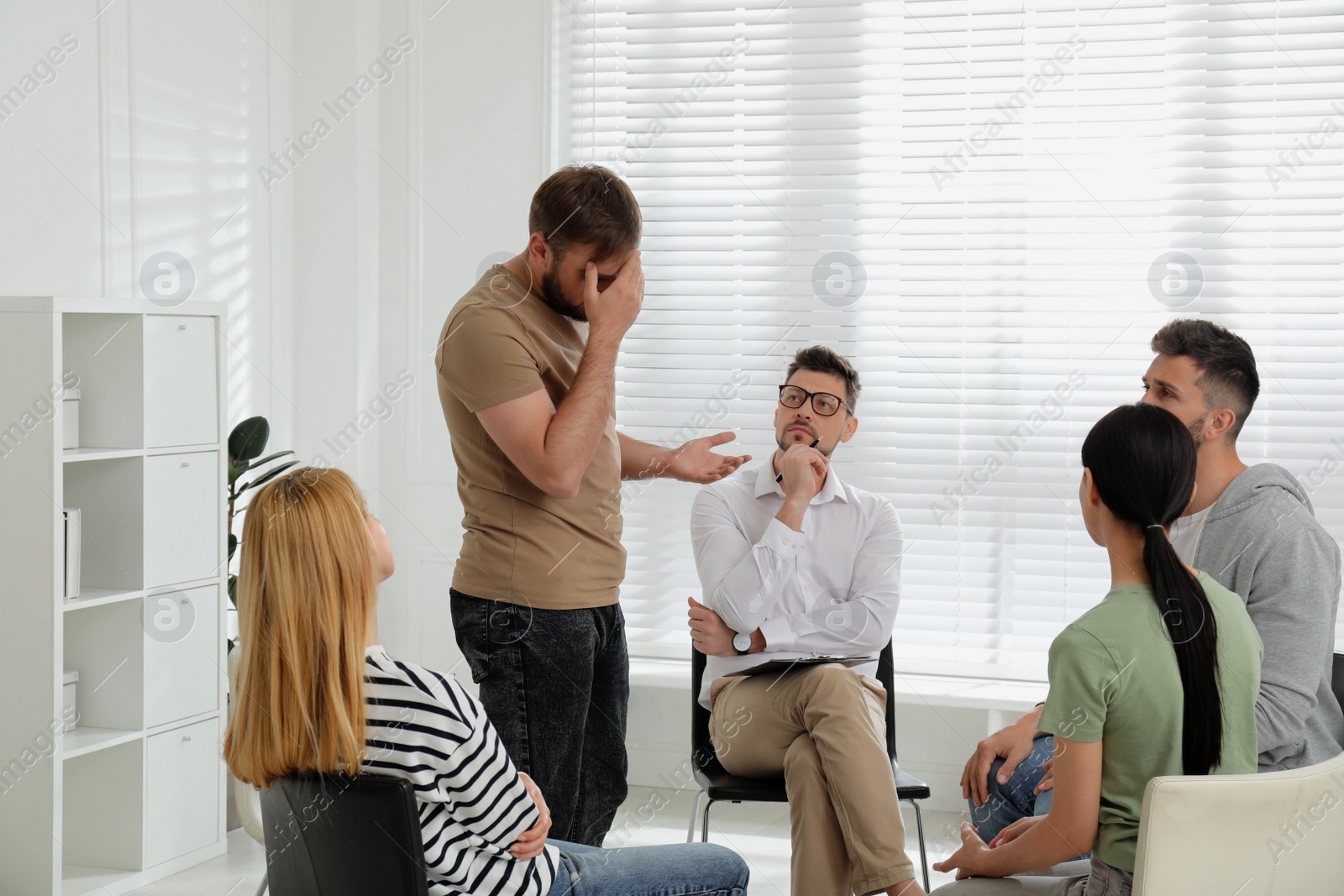 Photo of Psychotherapist working with group of drug addicted people at therapy session indoors