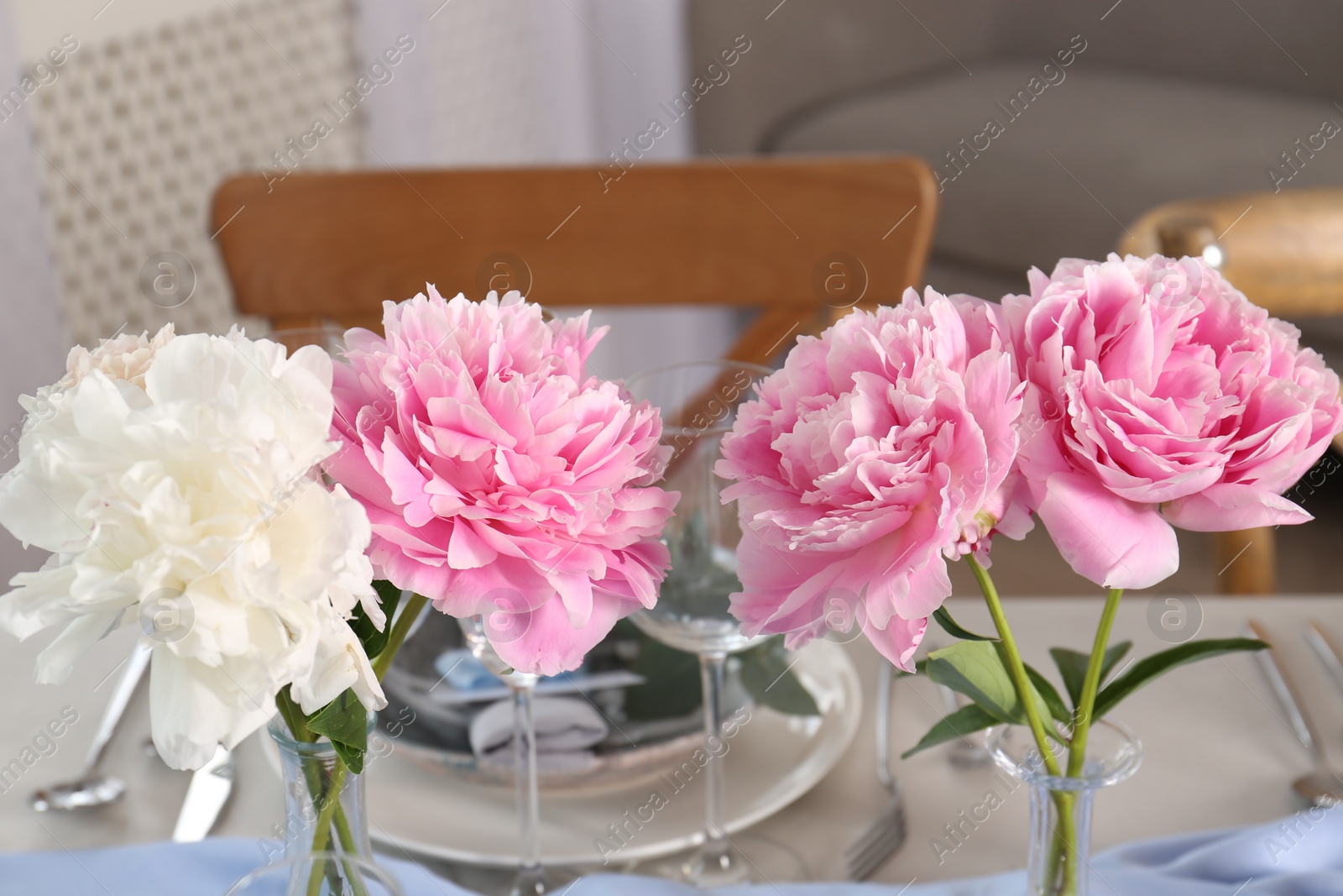 Photo of Beautiful table setting. Peonies near plate and cutlery on table indoors