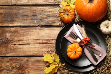 Festive table setting with pumpkins and space for text on wooden background, flat lay. Thanksgiving Day celebration