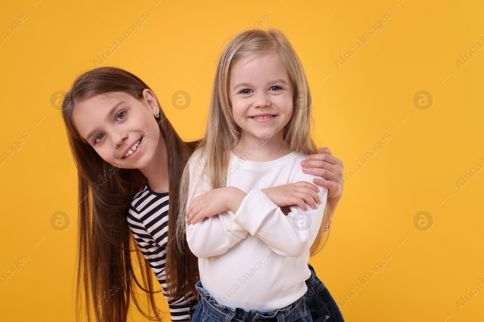 Photo of Portrait of cute little sisters on orange background