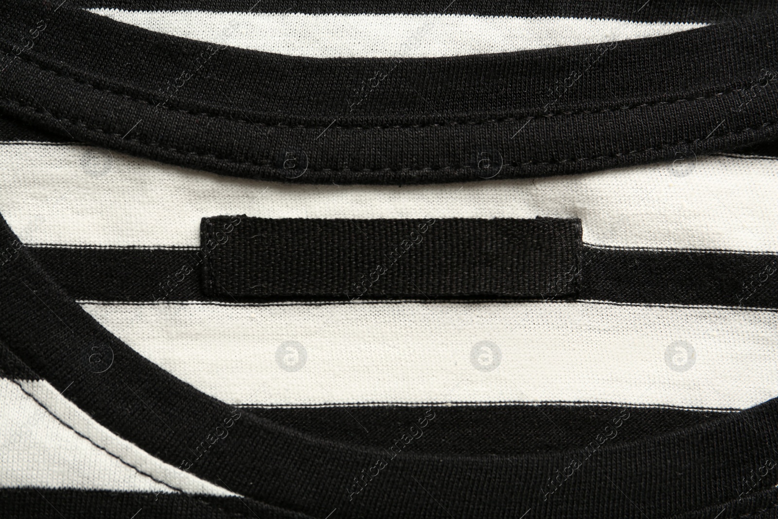 Photo of Blank clothing label on striped T-shirt, top view