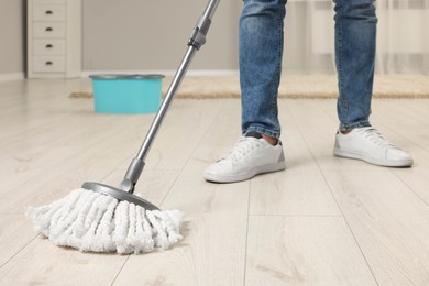 Man cleaning floor with mop at home, closeup