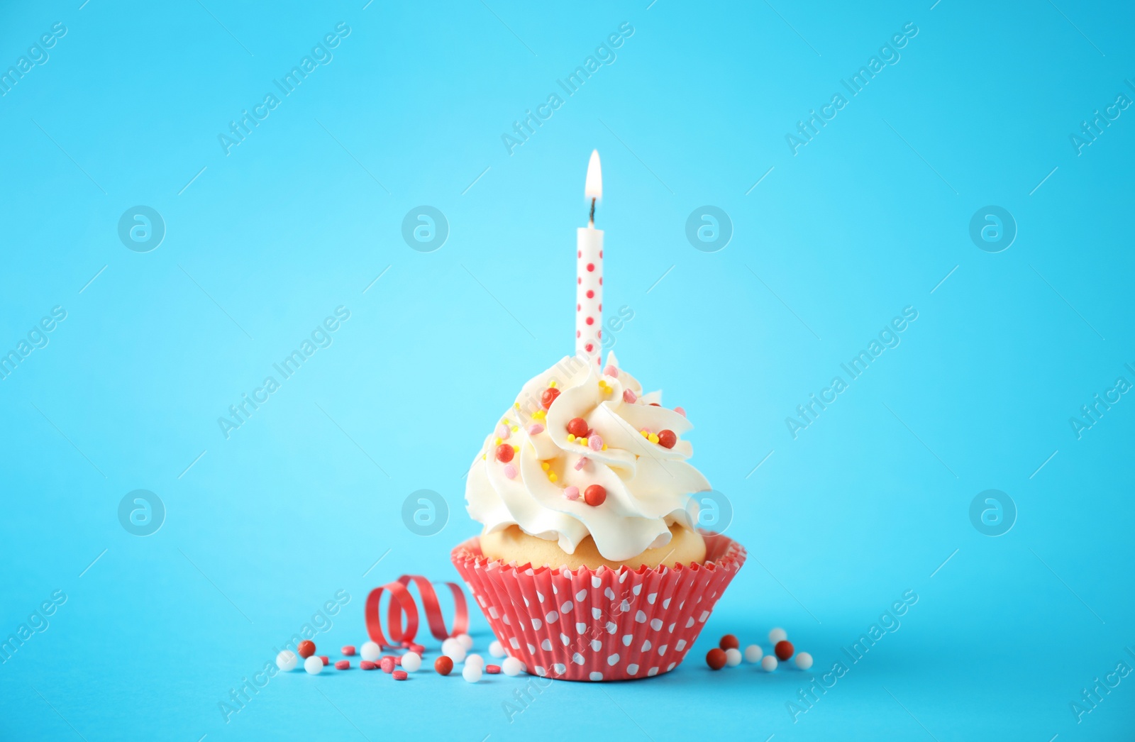 Photo of Delicious birthday cupcake with candle on light blue background