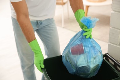 Photo of Man throwing garbage bag into bin at home, closeup