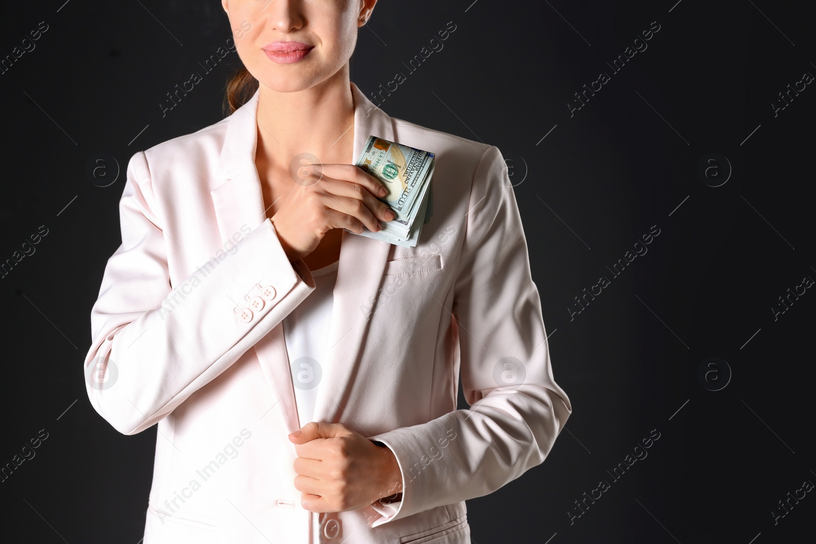 Photo of Woman putting bribe into pocket on black background, closeup