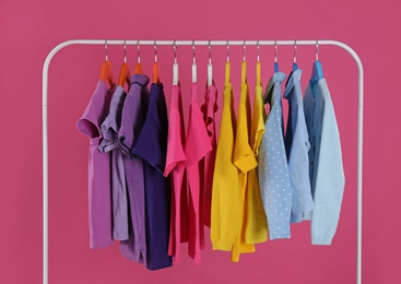 Photo of Rack with stylish children clothes on pink background
