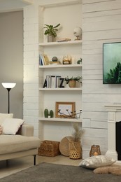 Photo of Sofa near shelves with different decor in room. Interior design