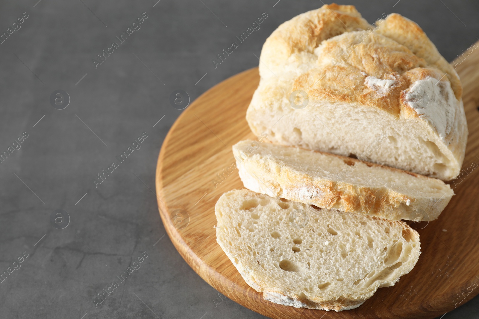 Photo of Freshly baked cut sourdough bread on grey table, closeup. Space for text