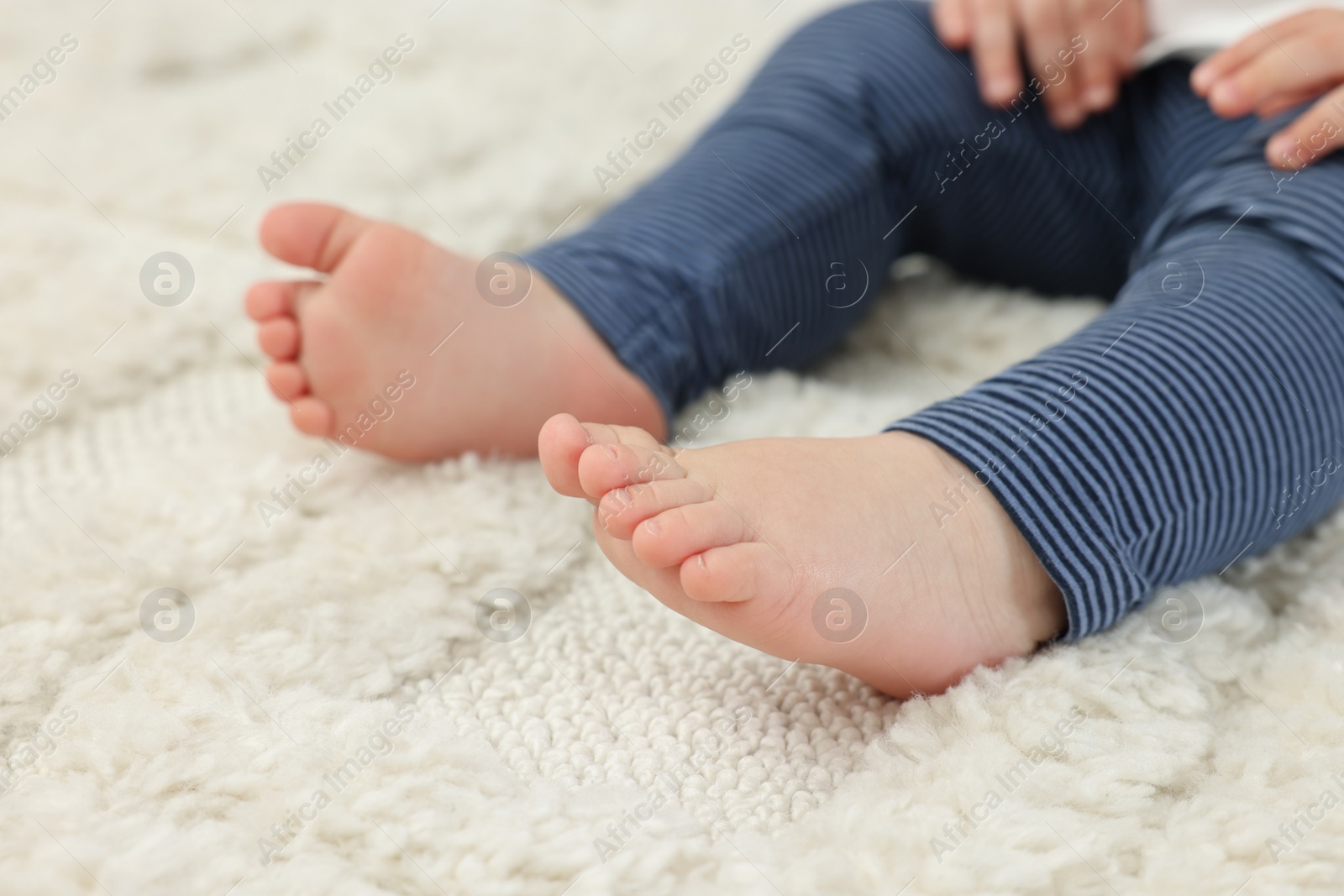 Photo of Baby sitting on soft carpet, closeup view