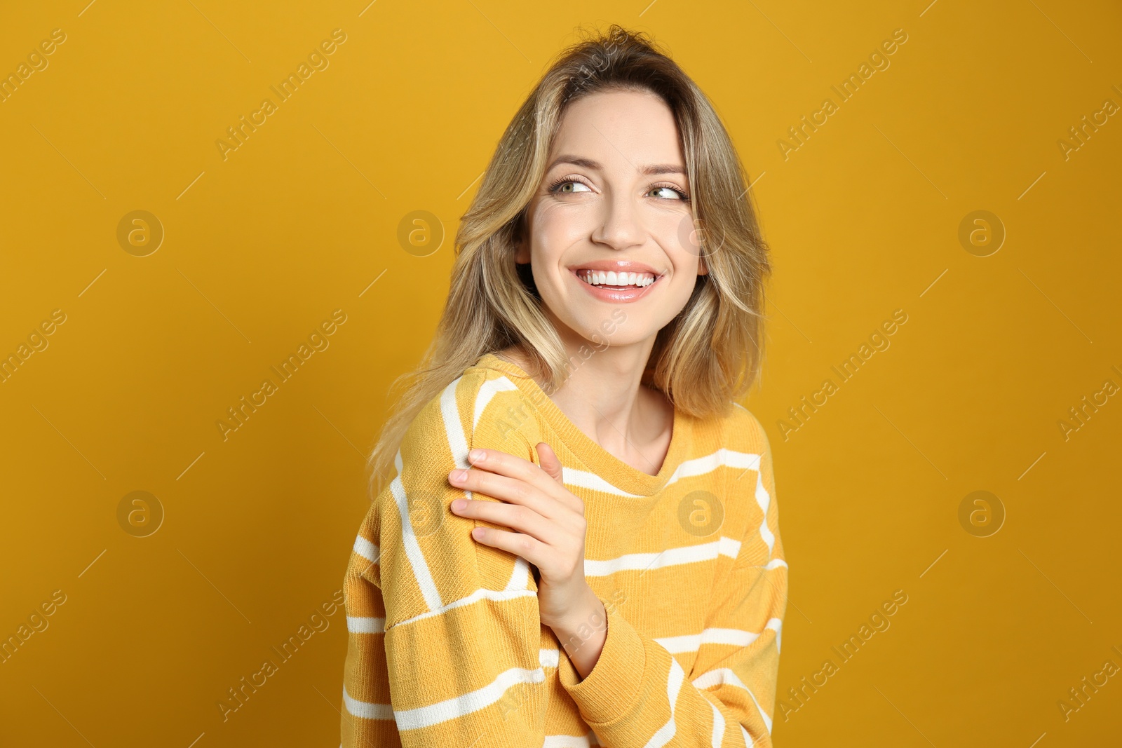 Photo of Portrait of happy young woman with beautiful blonde hair and charming smile on yellow background