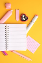 Flat lay composition with open notebook and different school stationery on yellow background, space for text. Back to school
