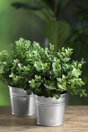 Photo of Different artificial potted herbs on wooden table outdoors