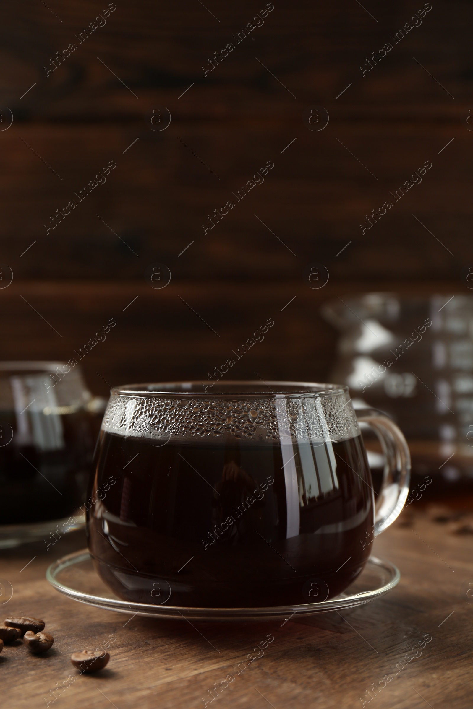 Photo of Hot coffee in glass cups and beans on wooden table, closeup. Space for text