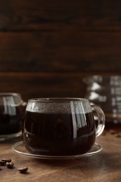 Photo of Hot coffee in glass cups and beans on wooden table, closeup. Space for text