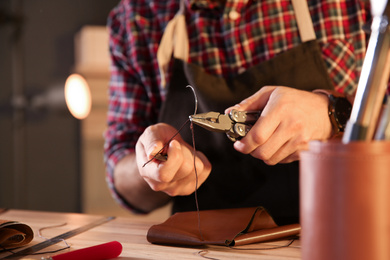 Photo of Man threading needle for leather working, closeup