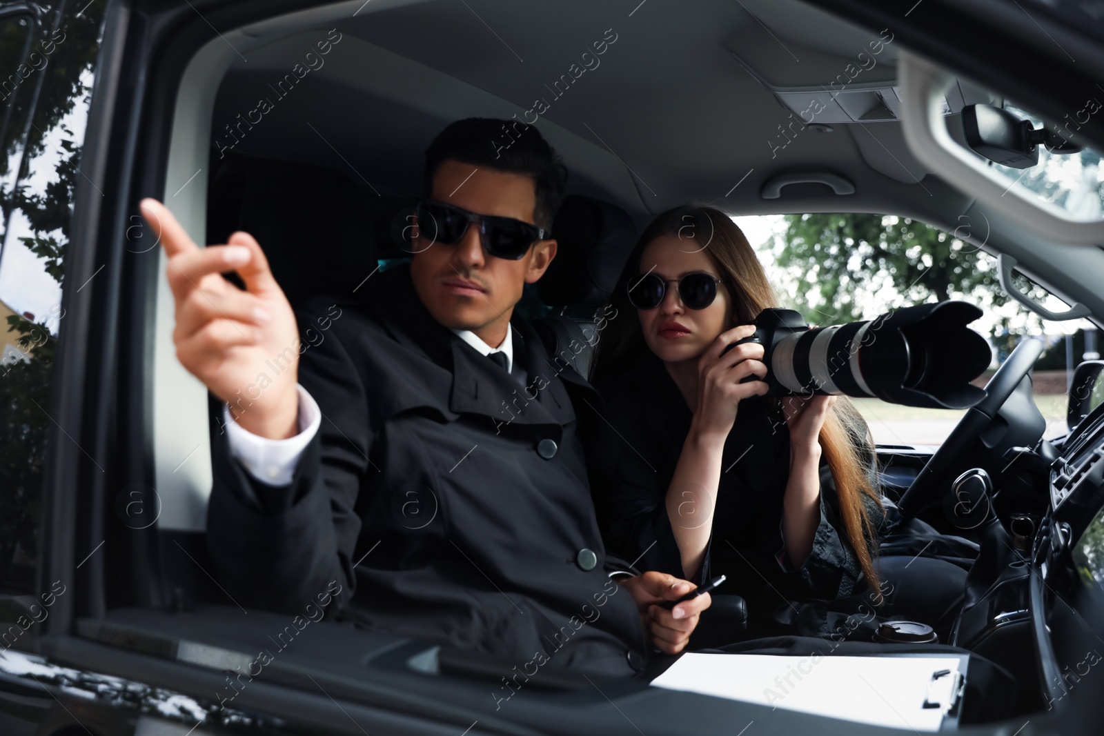 Photo of Private detectives with modern camera spying from car