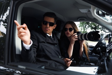 Photo of Private detectives with modern camera spying from car