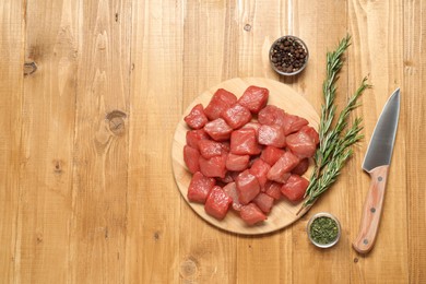 Photo of Cooking delicious goulash. Raw beef meat, knife and different spices on wooden table, flat lay. Space for text