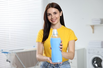 Photo of Woman holding fabric softener in bathroom, space for text