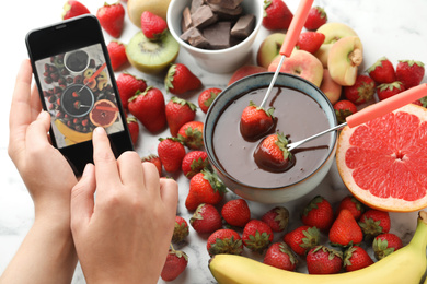 Photo of Blogger taking picture of chocolate fondue and fruits at table, closeup