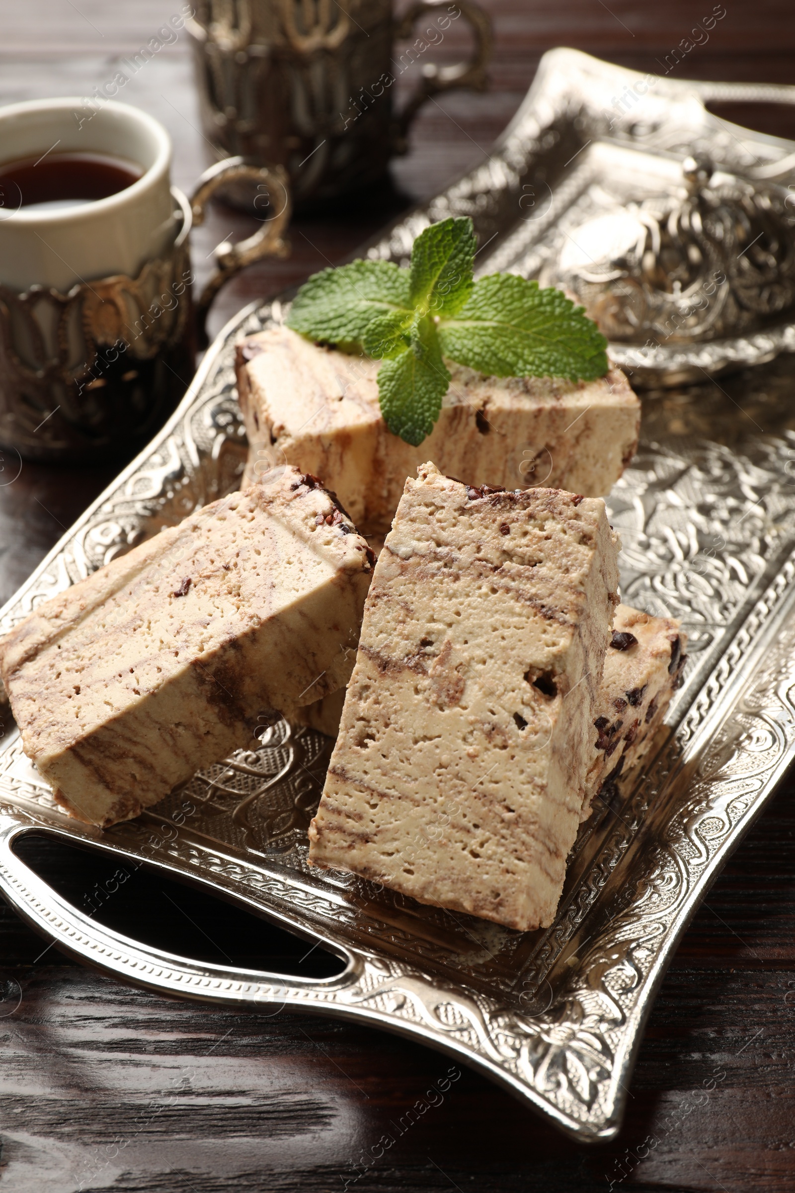 Photo of Tasty chocolate halva and mint on wooden table, closeup