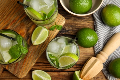 Photo of Delicious mojito and ingredients on wooden table, flat lay