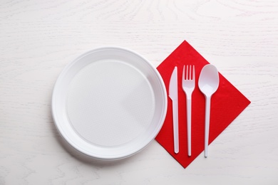 Composition with plastic dishware on wooden table, flat lay. Picnic table setting